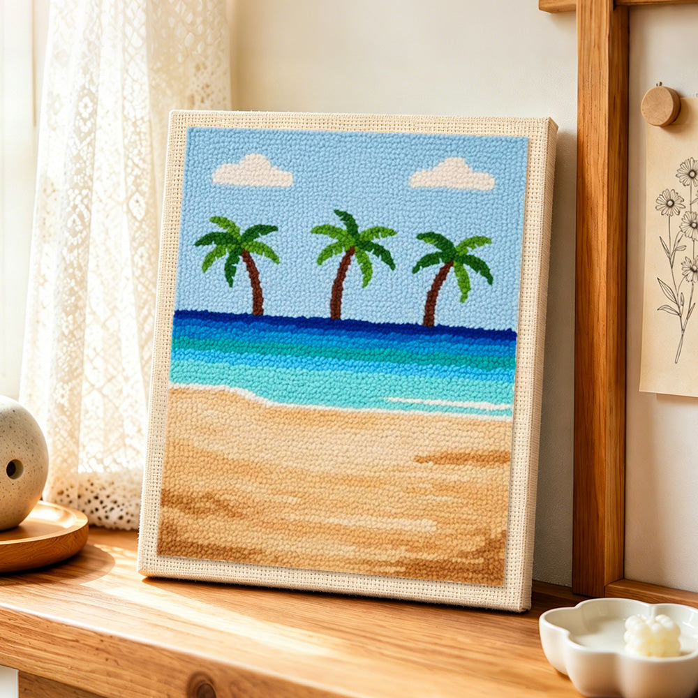 Three palm trees and blue ocean punch needle artwork displayed on a table