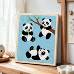 Three playful pandas punch needle artwork displayed on a table