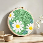 Three pure white daisies punch needle artwork displayed on a table