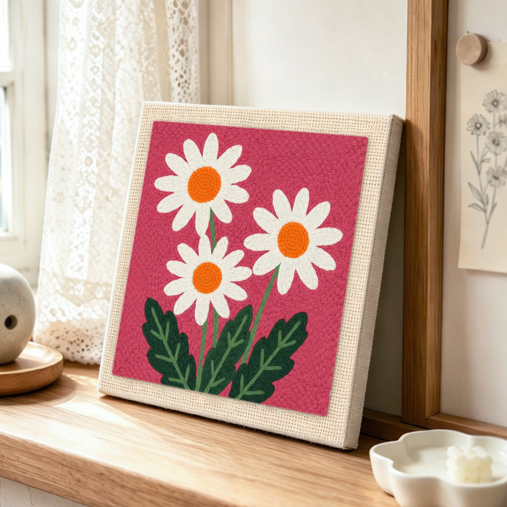 Three simple daisy flowers punch needle artwork displayed on a table