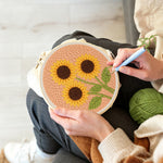 Creating handmade three sunflowers on peachy pink punch needle artwork