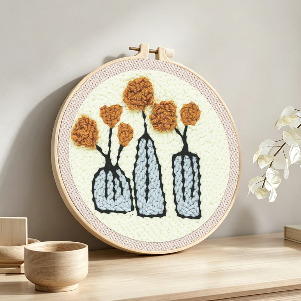 Three vases with flowers punch needle artwork displayed on a table