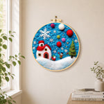 Tiny scene with red house and snowflake needle felt wall art displayed in a bright home interior