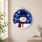 Top hat snowman with falling snowflakes needle felt wall art displayed in a bright home interior