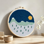 Tranquil mountain scenery punch needle artwork displayed on a table