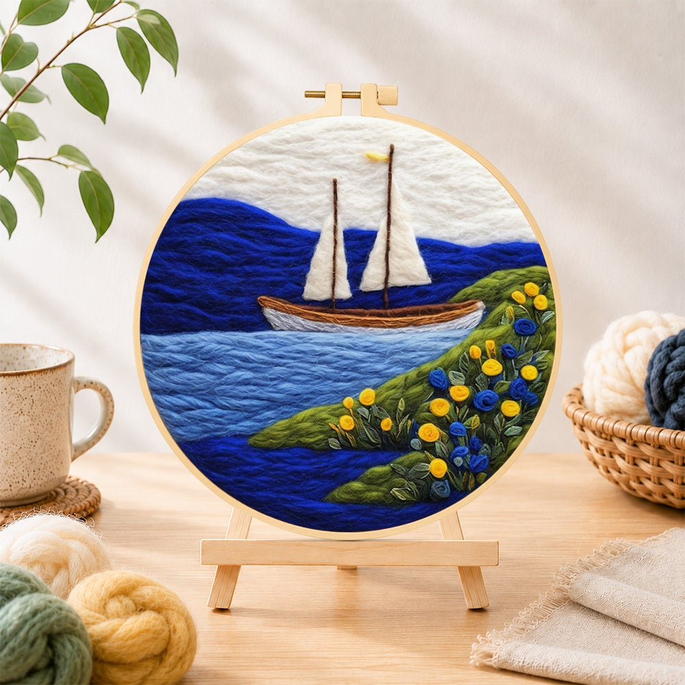 Finished tranquil white sailboat and floral shoreline needle felting displayed on a wooden easel