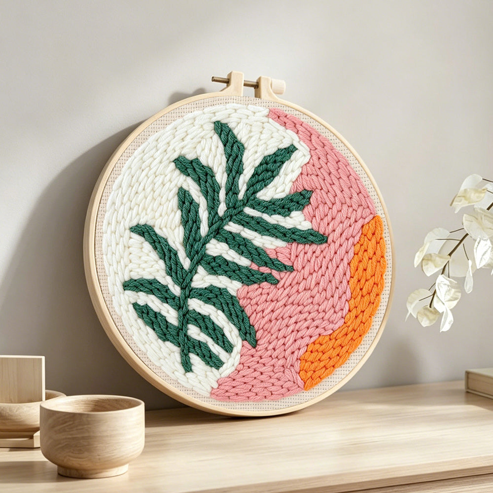 Tropical leaf and sunset tones punch needle artwork displayed on a table
