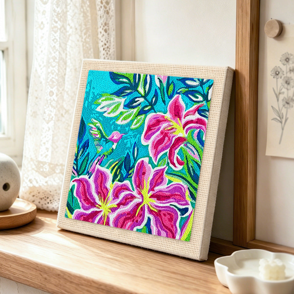 Tropical lily flowers and hummingbird punch needle artwork displayed on a table