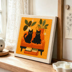 Two black cats on a sofa punch needle artwork displayed on a table