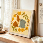 Two bunnies kissing punch needle artwork displayed on a table