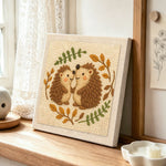 Two hedgehogs in love punch needle artwork displayed on a table