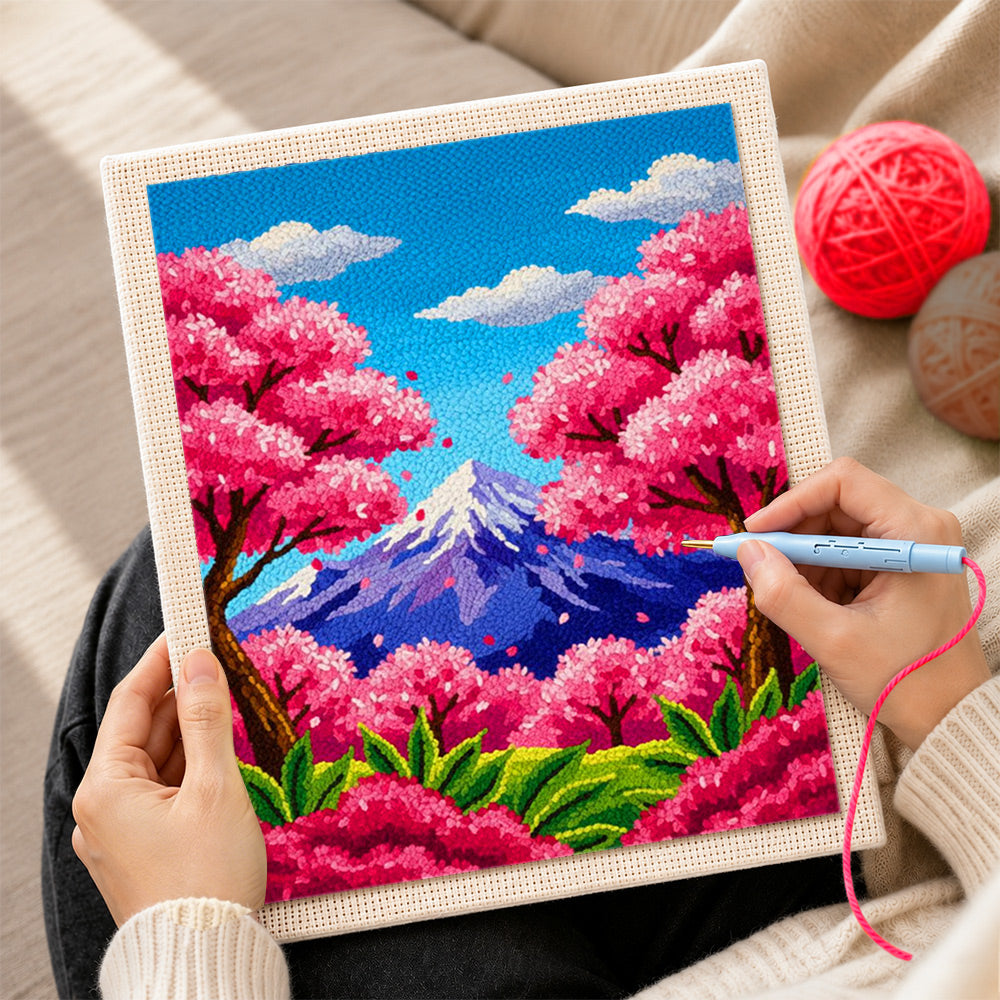 Creating handmade vibrant cherry blossom trees and snowy peak punch needle artwork