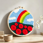 Vibrant rainbow with red roses punch needle artwork displayed on a table