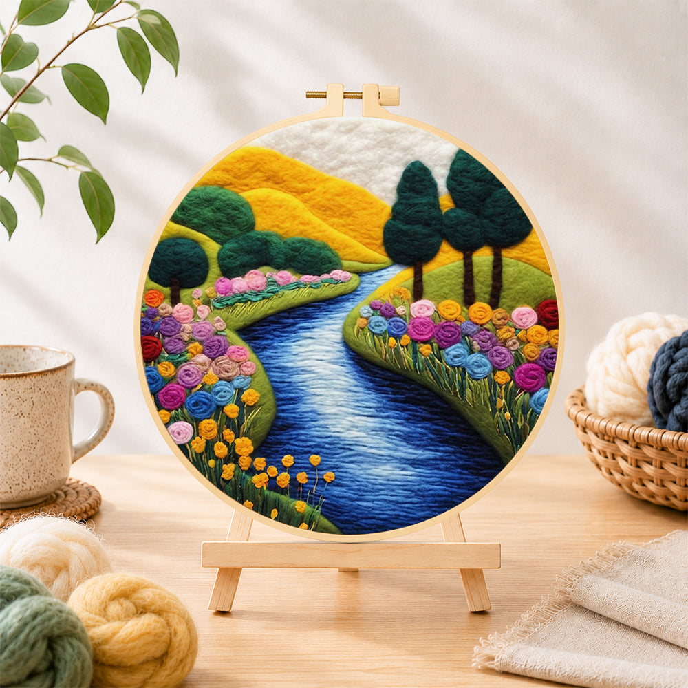 Finished vibrant rolling hills, sunny river and rainbow flowers needle felting displayed on a wooden easel