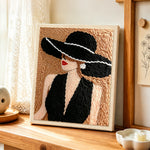 Vintage lady in black hat punch needle artwork displayed on a table