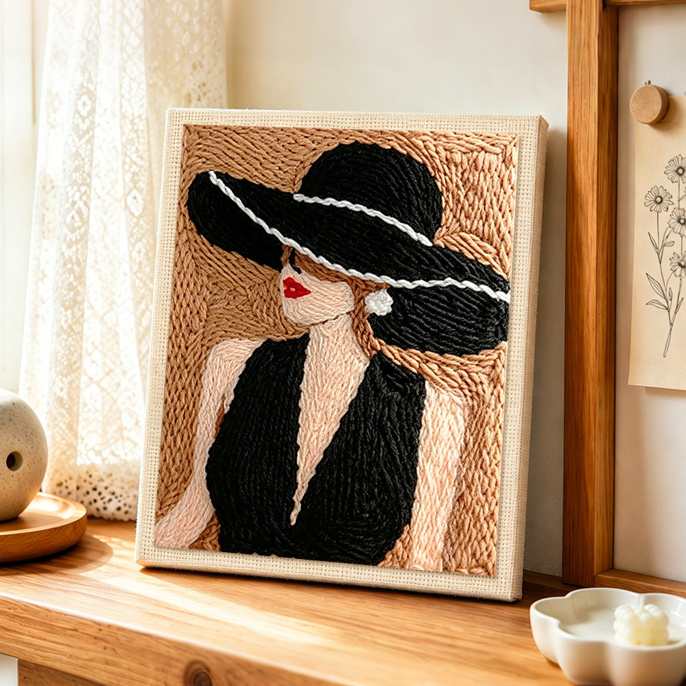 Vintage lady in black hat punch needle artwork displayed on a table
