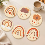 Warm-toned rainbow and cloud punch needle coasters used for home decoration