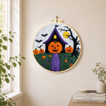 Weird pumpkin head house needle felt wall art displayed in a bright home interior