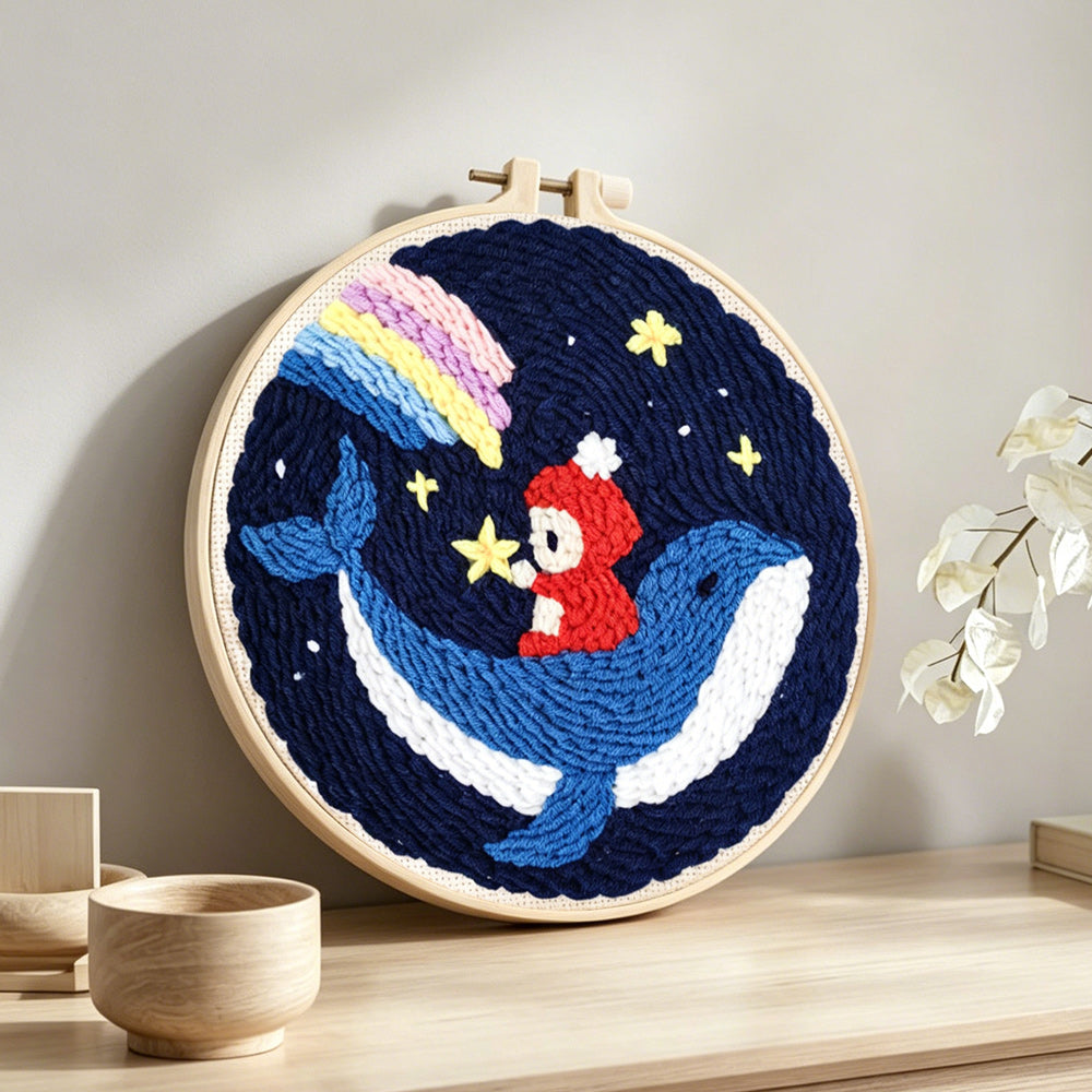 Whale and astronaut in starry night sky punch needle artwork displayed on a table