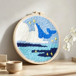 Whale and iceberg ocean punch needle artwork displayed on a table