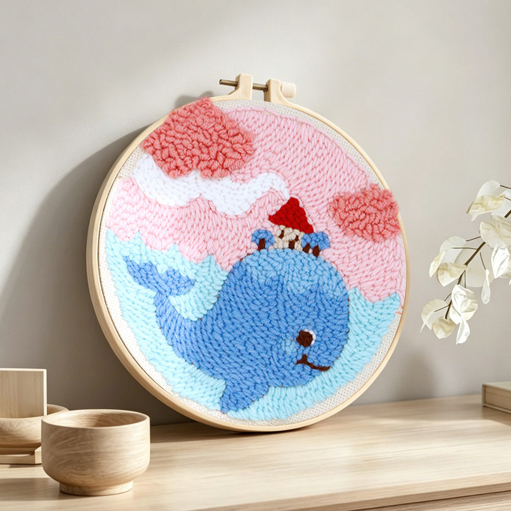 Whale carrying a small house in dreamy sky punch needle artwork displayed on a table
