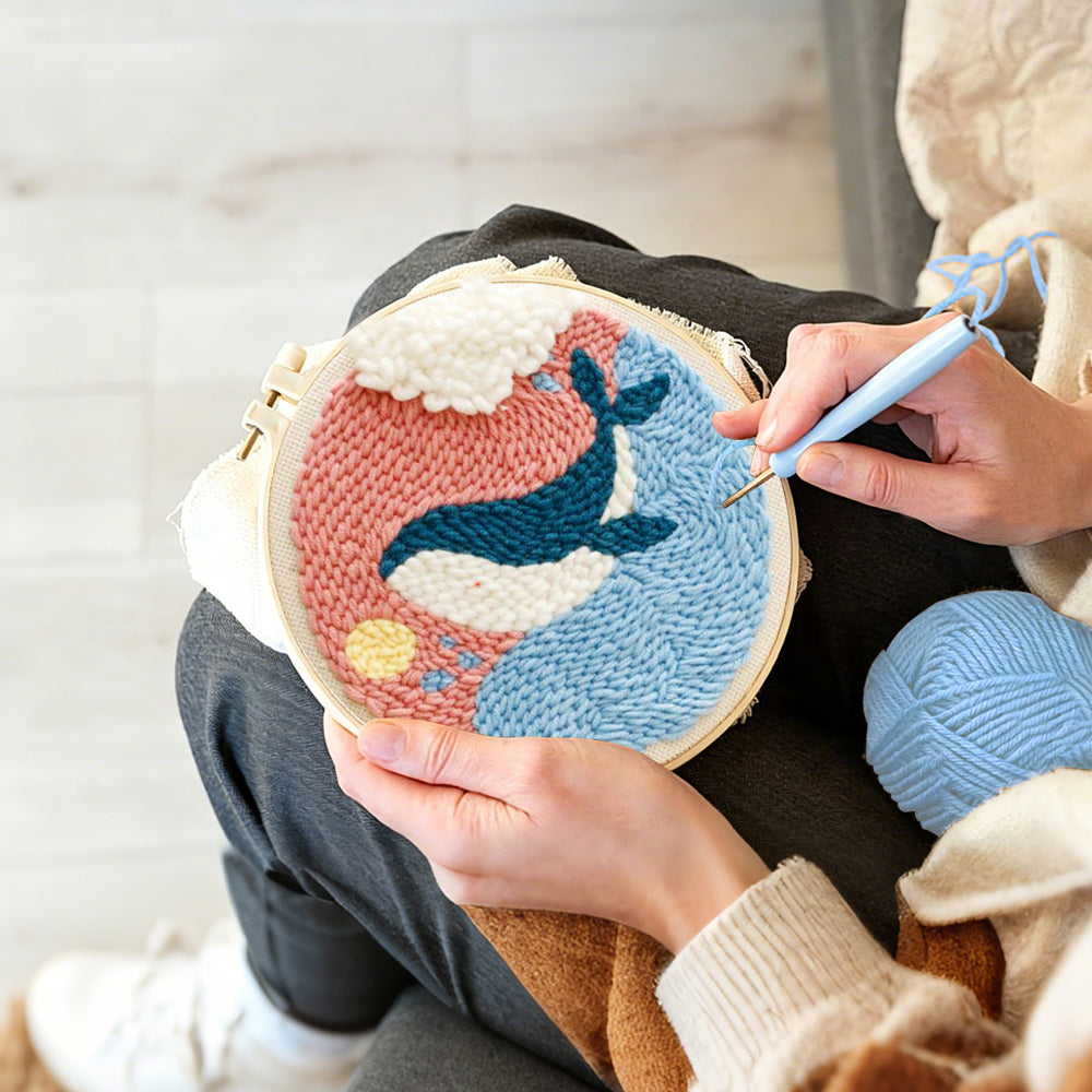Creating handmade whale jumping out of ocean in pink sky punch needle artwork