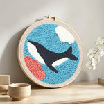 Whale swimming under the sea punch needle artwork displayed on a table