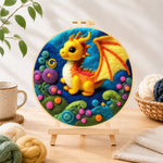 Finished whimsical baby dragon and colourful spiral plant needle felting displayed on a wooden easel