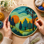 Creating the whimsical forest and rolling mountains wool painting by hand with a felting needle
