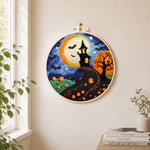 Whimsical haunted village and halloween pumpkins needle felt wall art displayed in a bright home interior