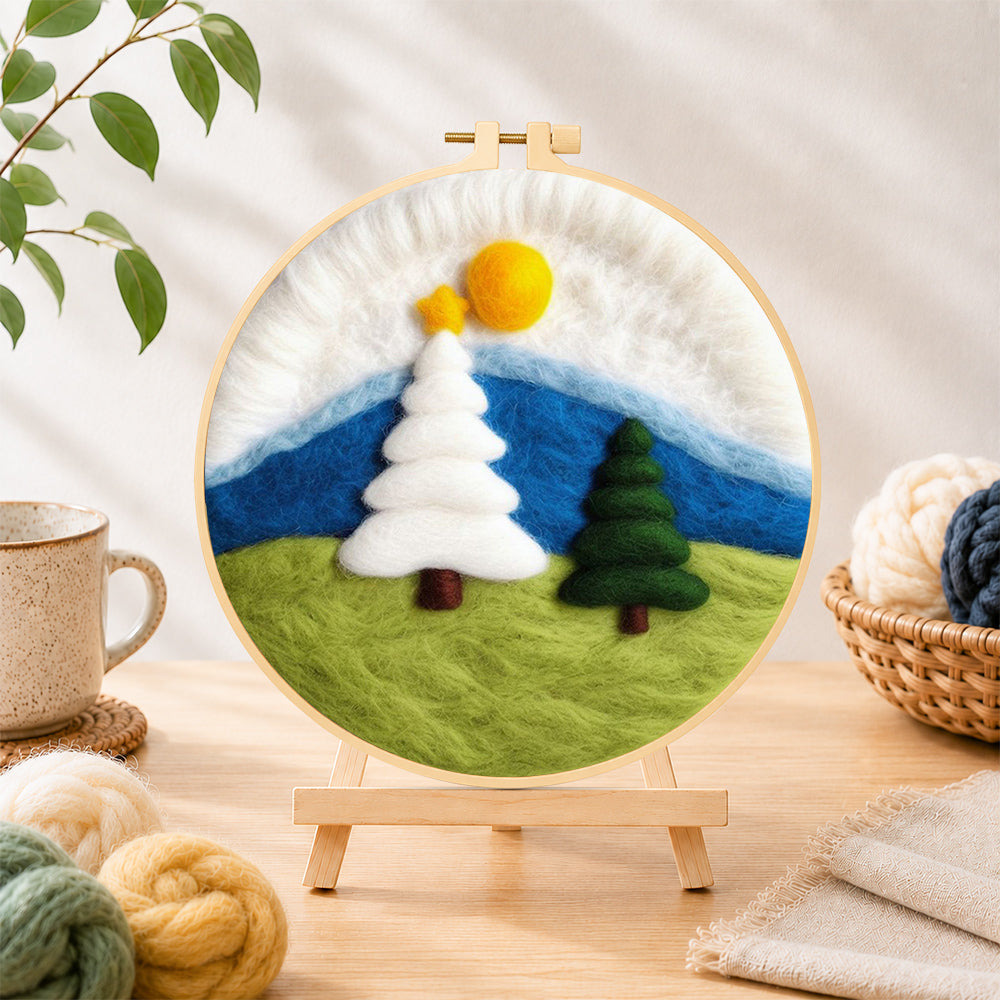 Finished white and green christmas trees on grass needle felting displayed on a wooden easel