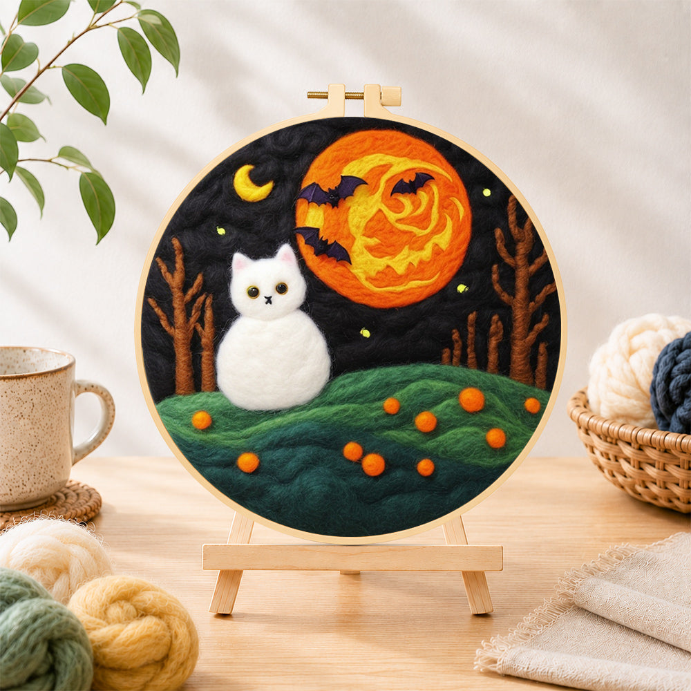 Finished white cat and spooky orange moon needle felting displayed on a wooden easel
