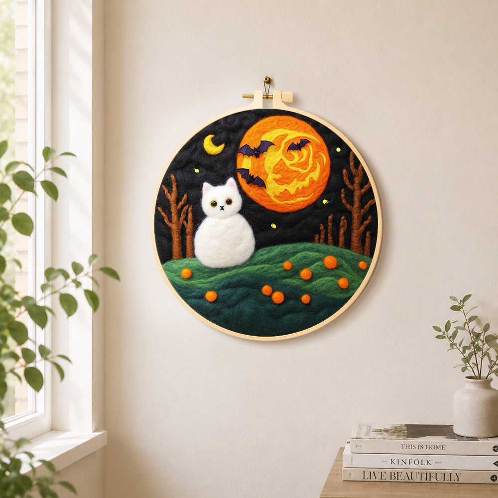 White cat and spooky orange moon needle felt wall art displayed in a bright home interior