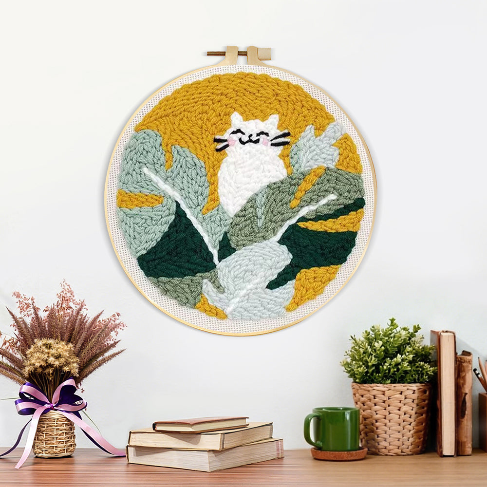 Finished white cat in green leaves artwork displayed on a wall