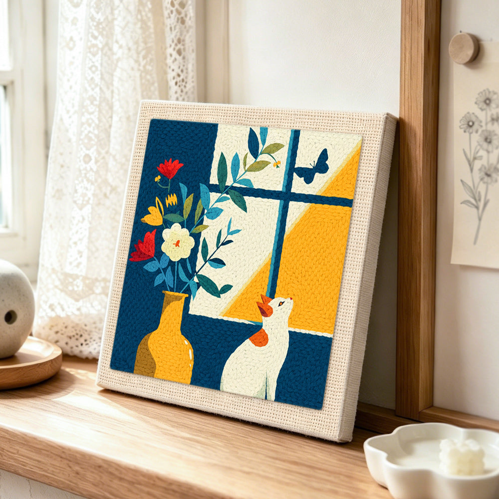 White cat looking at a butterfly punch needle artwork displayed on a table