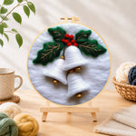 Finished white christmas bells with holly needle felting displayed on a wooden easel