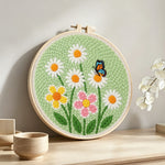 White daisies and butterfly punch needle artwork displayed on a table