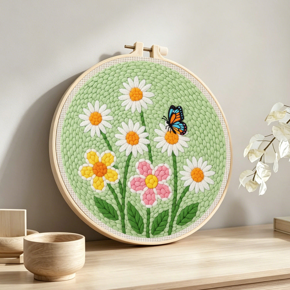 White daisies and butterfly punch needle artwork displayed on a table