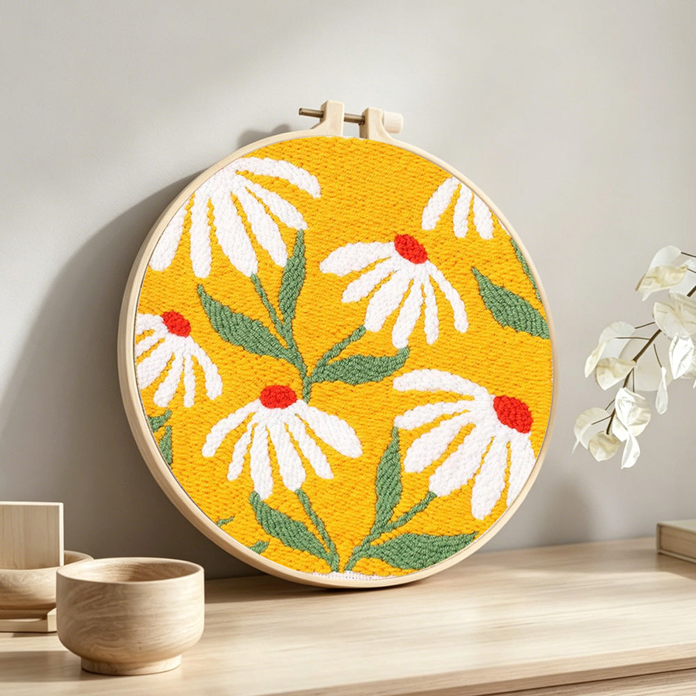 White daisies on a yellow background punch needle artwork displayed on a table