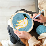 Creating handmade white dove and olive leaf punch needle artwork