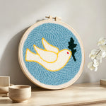White dove and olive leaf punch needle artwork displayed on a table