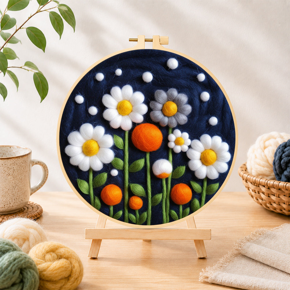 Finished white flowers and orange orbs on navy needle felting displayed on a wooden easel