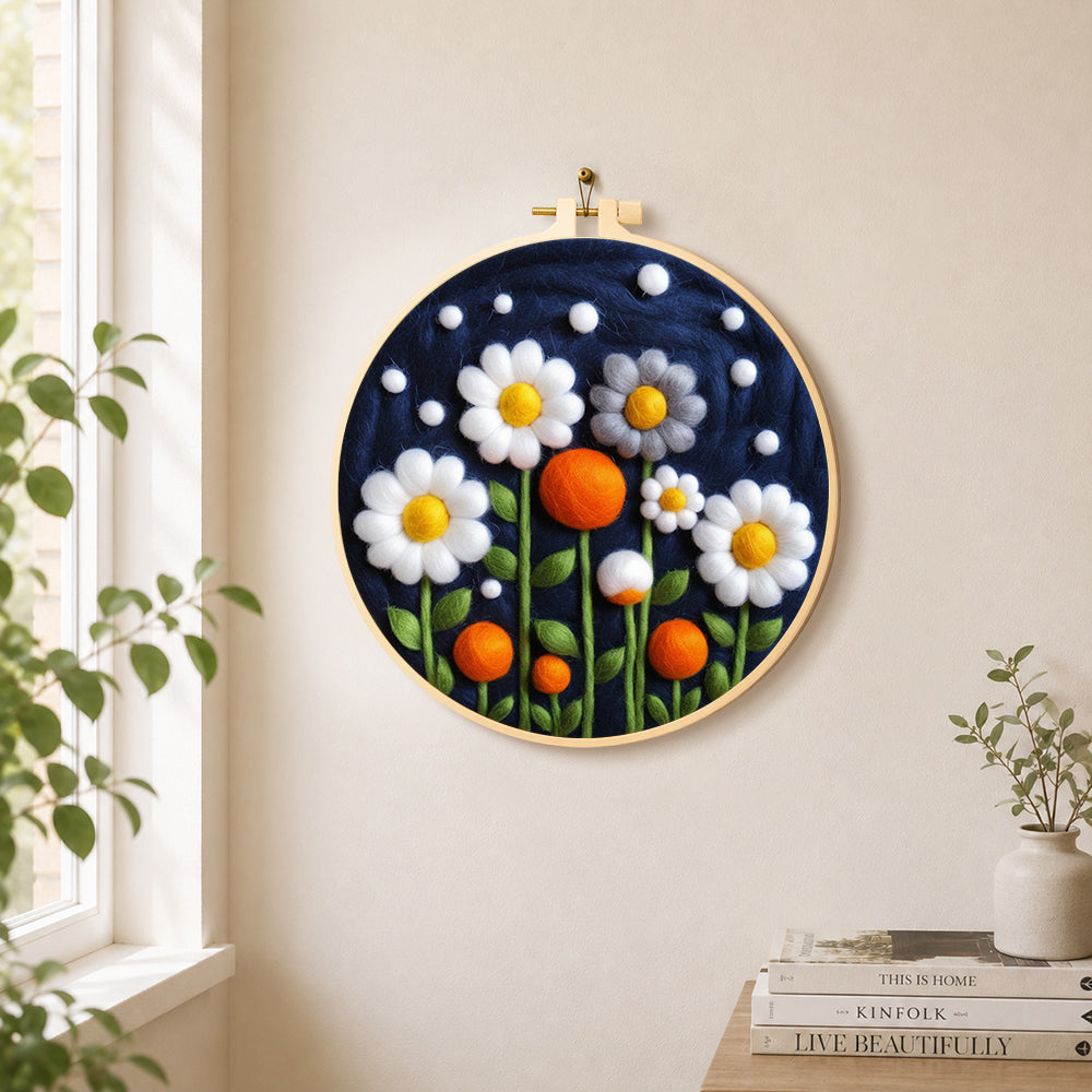 White flowers and orange orbs on navy needle felt wall art displayed in a bright home interior