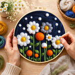 Creating the white flowers and orange orbs on navy wool painting by hand with a felting needle