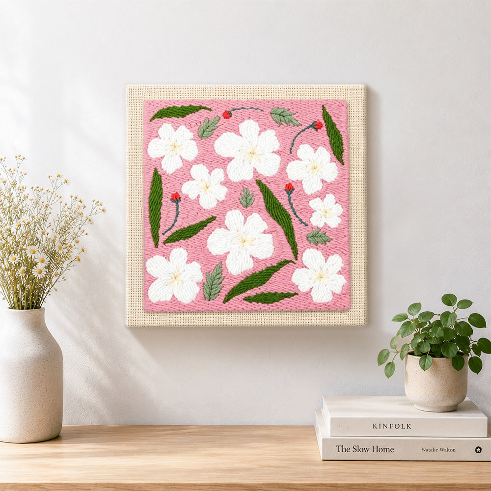 Finished white flowers with green leaves artwork displayed on a wall