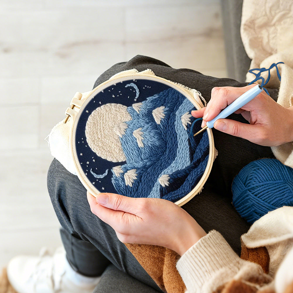 Creating handmade white moon above blue snowy mountains punch needle artwork