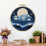Finished white moon above blue snowy mountains artwork displayed on a wall