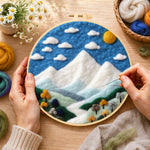 Creating the white mountain peaks under the blue sky wool painting by hand with a felting needle