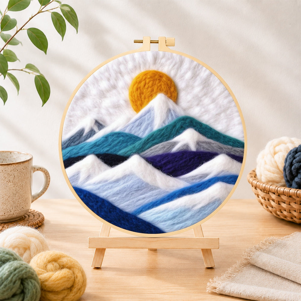 Finished white snow mountains and golden spiral sun needle felting displayed on a wooden easel