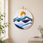 White snow mountains and golden spiral sun needle felt wall art displayed in a bright home interior